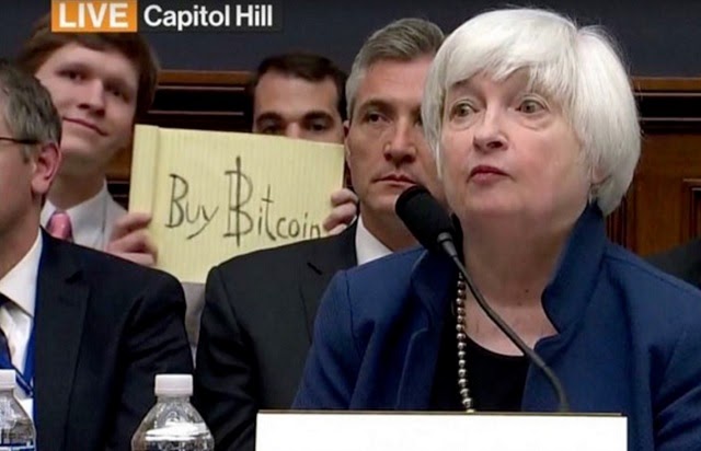 A buy bitcoin sign being held up on TV during a Congress hearing.